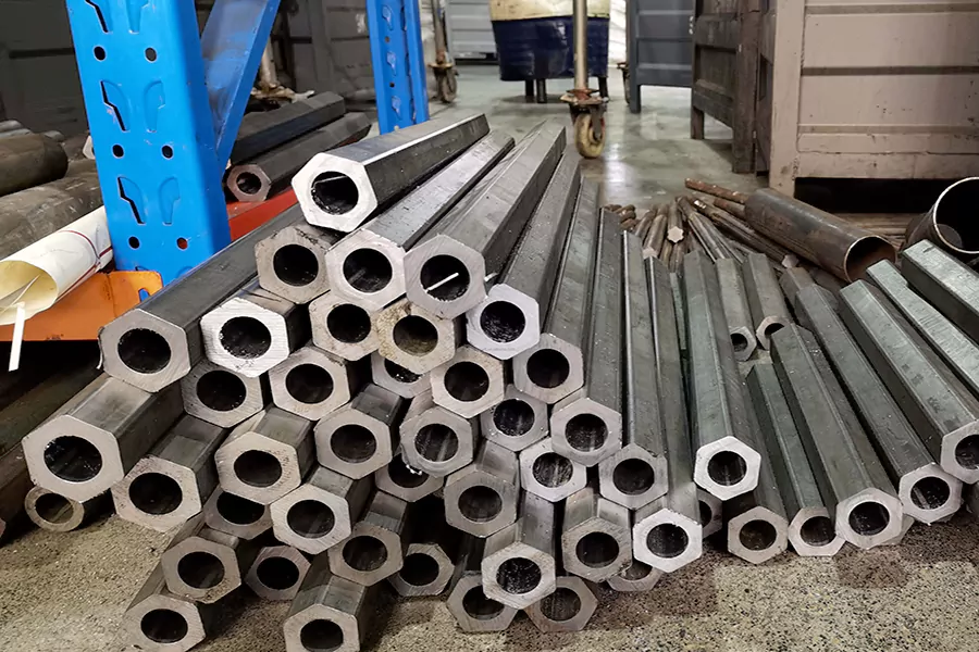 The picture shows a large pile of hexagonal steel pipes placed on the factory floor