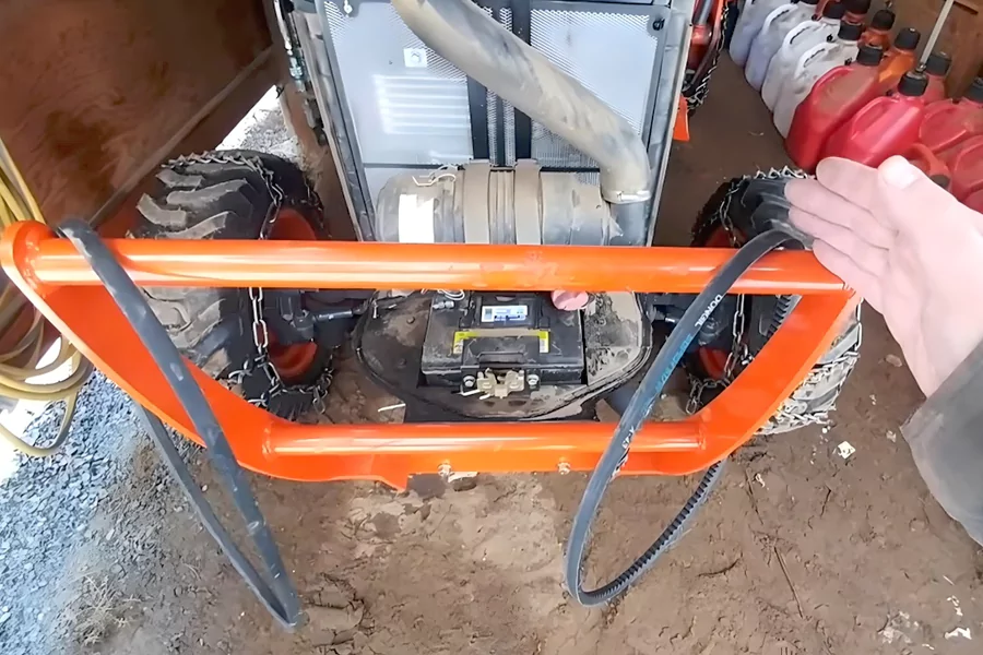This picture shows two belts placed on a tractor, and an engineer is explaining how to replace the belts