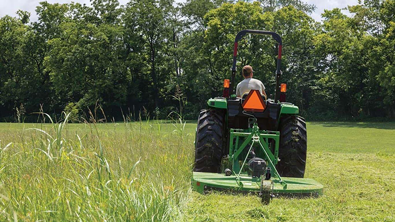 Rotary cutter tractor blade cutting grass and weeds