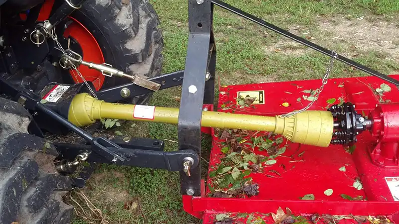 PTO shaft with safety guard connecting a tractor to a rotary cutter